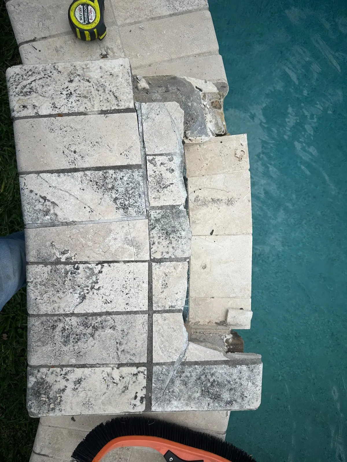Damaged pool coping and tile edge being evaluated for water loss